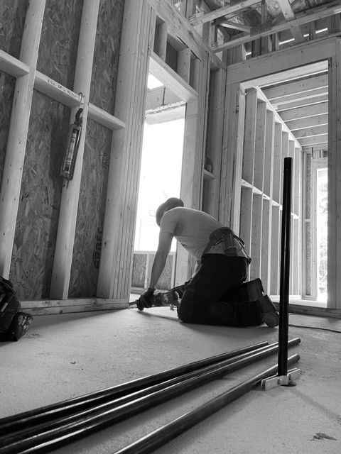 Un homme est agenouillé sur le sol dans un bâtiment en construction.