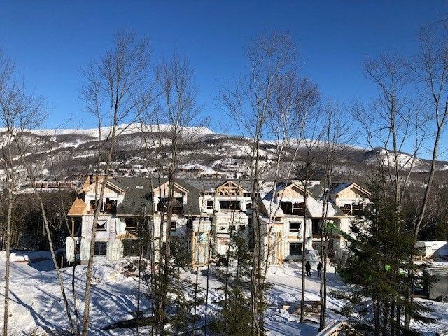 Un groupe de maisons est en cours de construction dans la neige avec des montagnes en arrière-plan.