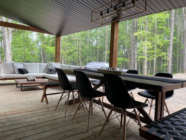 Il y a une table et des chaises sur la terrasse avec vue sur les bois.