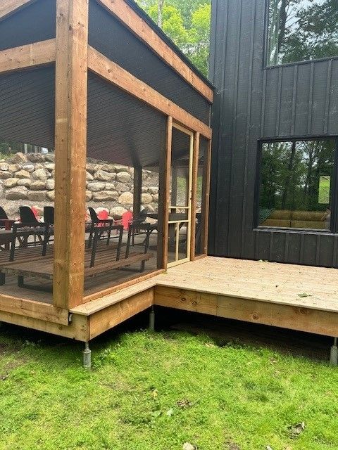 Une maison avec un porche grillagé et une terrasse en bois
