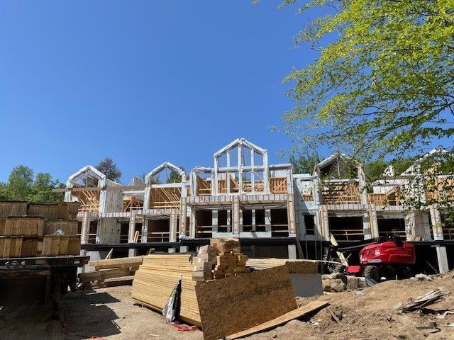 Une grande maison est en construction au milieu d'un champ de terre.