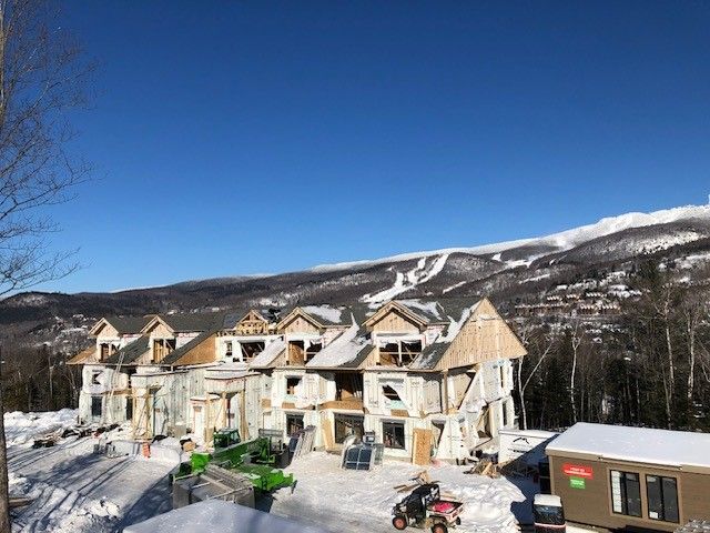 Une grande maison est en construction au sommet d'une colline couverte de neige.