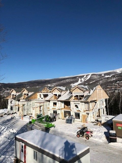 Un bâtiment en construction sous la neige avec des montagnes en arrière-plan