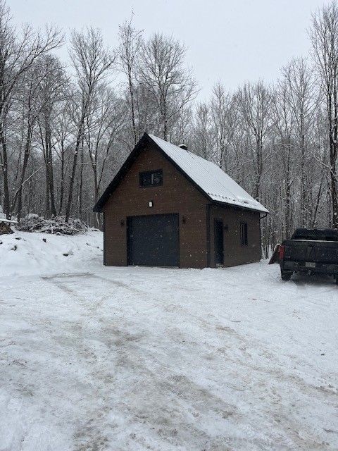 Un garage est recouvert de neige et un camion est garé devant.