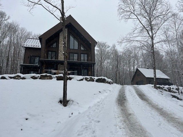 Une allée enneigée menant à une grande maison dans les bois