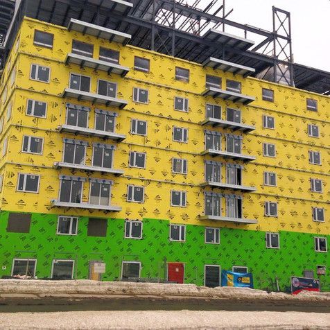Un grand bâtiment jaune et vert en construction avec beaucoup de fenêtres.