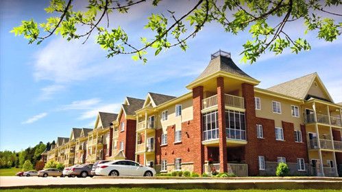 Un grand immeuble d'appartements avec des voitures garées devant.