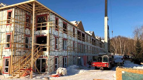 Un grand bâtiment est en construction dans la neige avec une grue en arrière-plan.