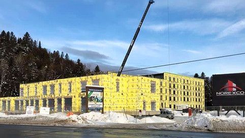 Un grand bâtiment est en construction dans la neige avec une grue au premier plan.