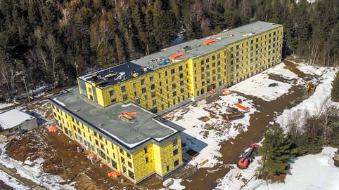 Une vue aérienne d'un grand bâtiment en construction au milieu d'une forêt enneigée.