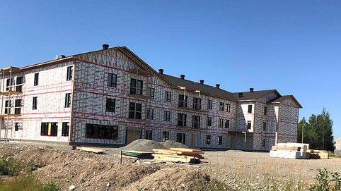 Un grand bâtiment en construction se trouve au sommet d'une colline de terre.