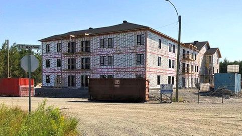 Un grand bâtiment en construction avec une benne à ordures devant.