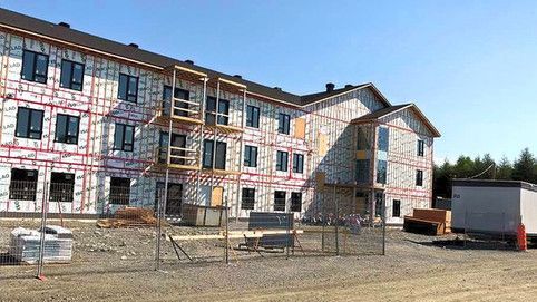 Un grand bâtiment est en construction au milieu d'un champ de terre.