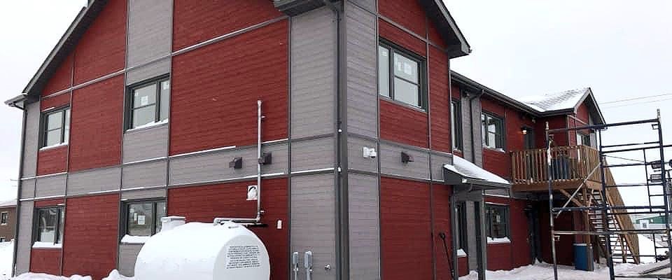 Un grand bâtiment en briques rouges avec un réservoir de propane devant.