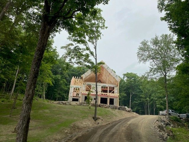 Une maison est en construction sur un chemin de terre entouré d'arbres