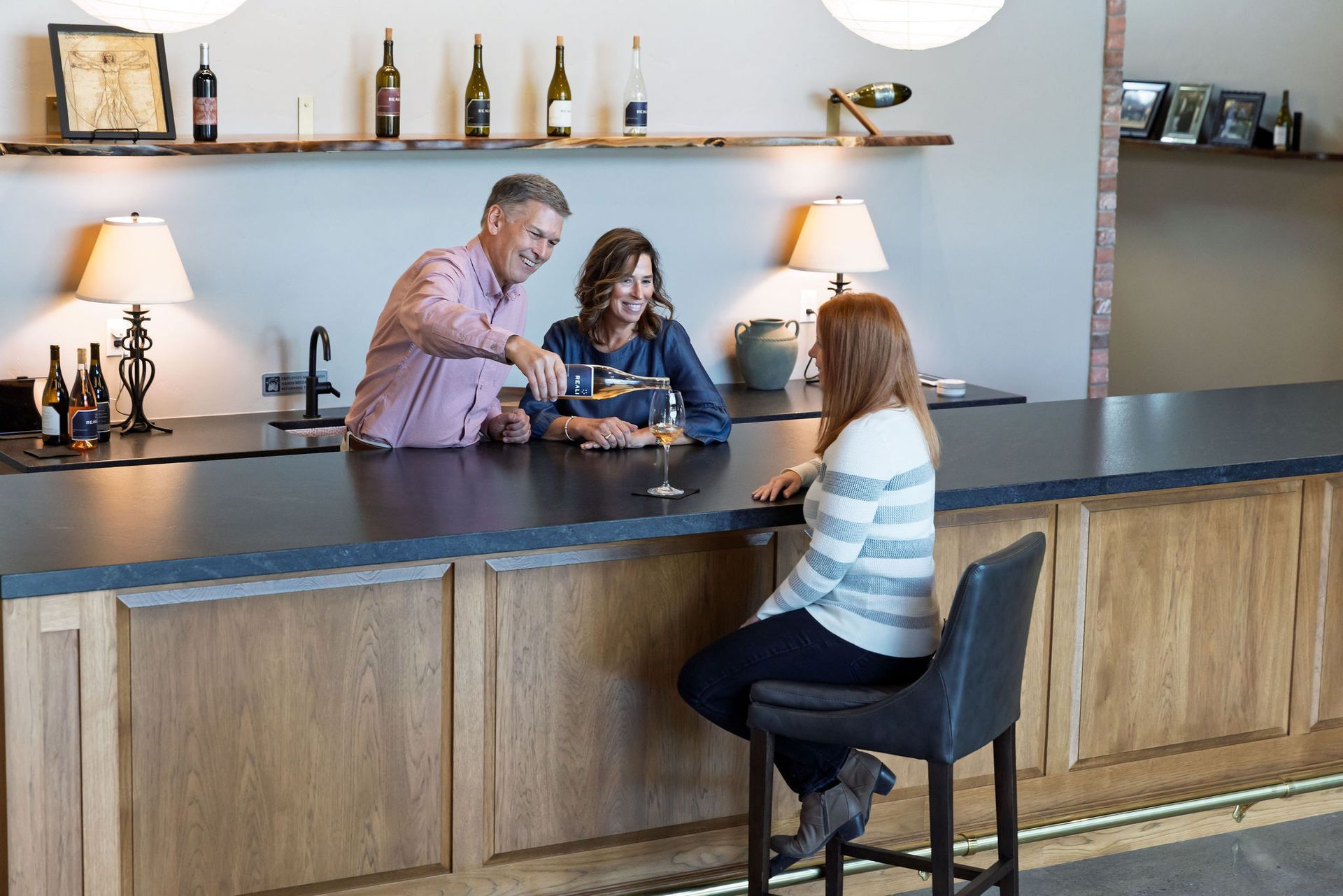 Ken, Kristin, and Serge cheers-ing their wine glasses in the vineyard