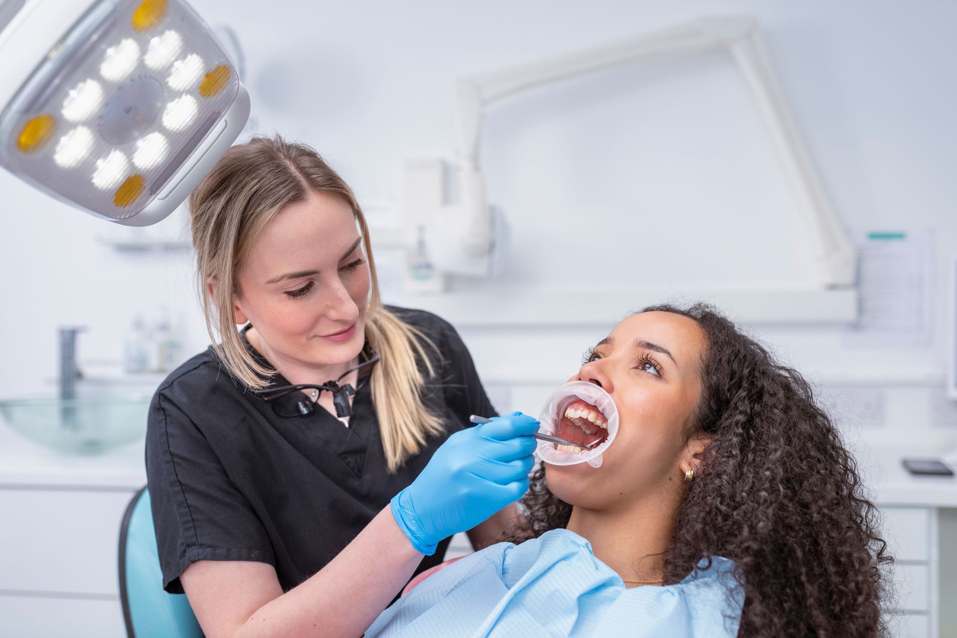 A dentist is checking the teeth of patient with a retractor. 