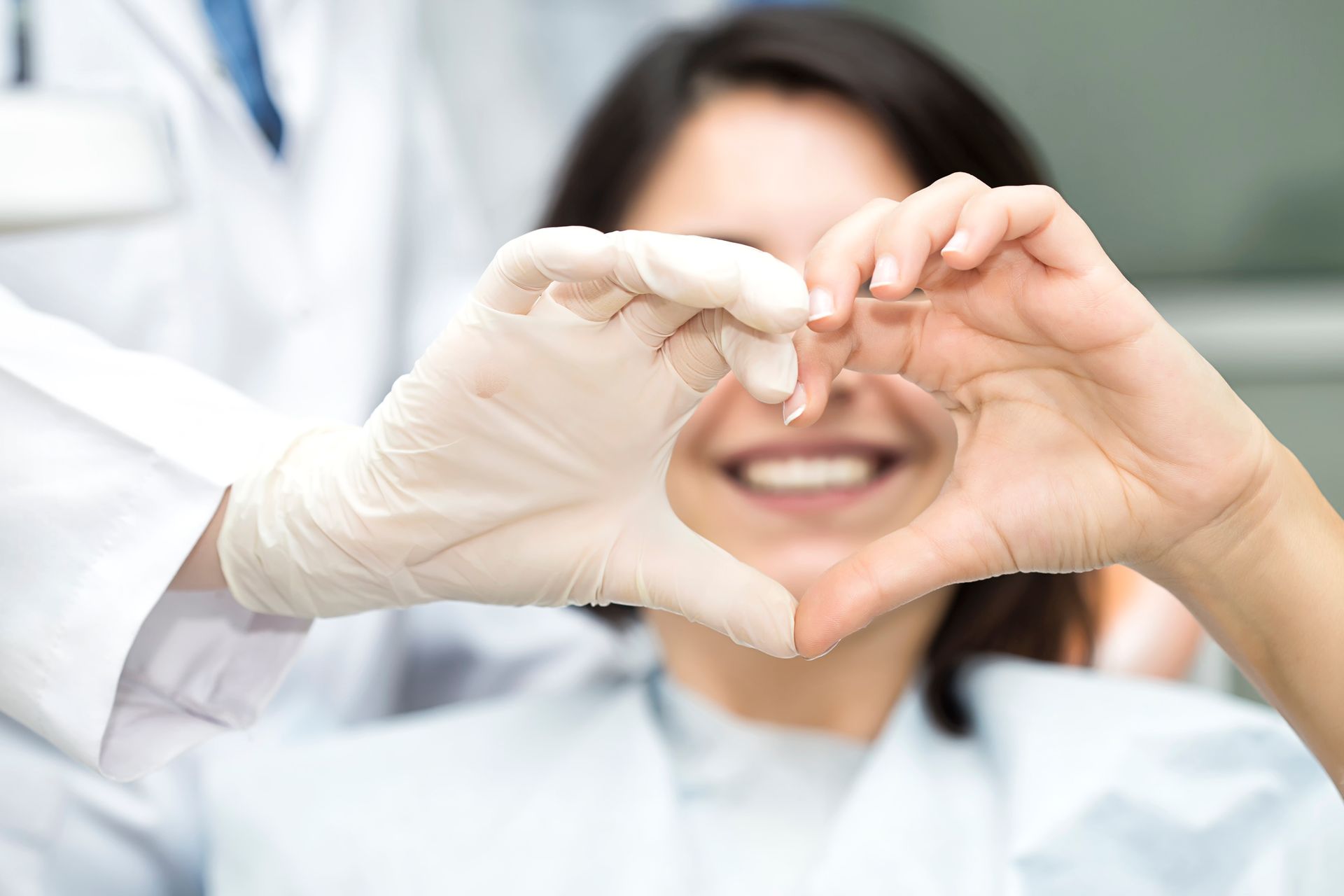 A woman is making a heart shape with her hands in front of her face.
