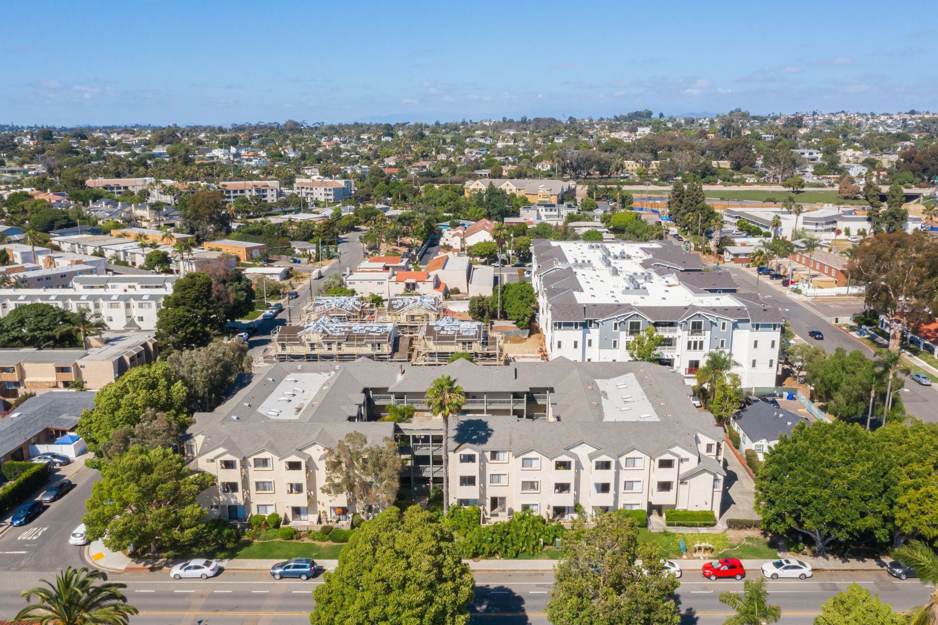 An aerial view of a large apartment building in a residential area surrounded by trees.