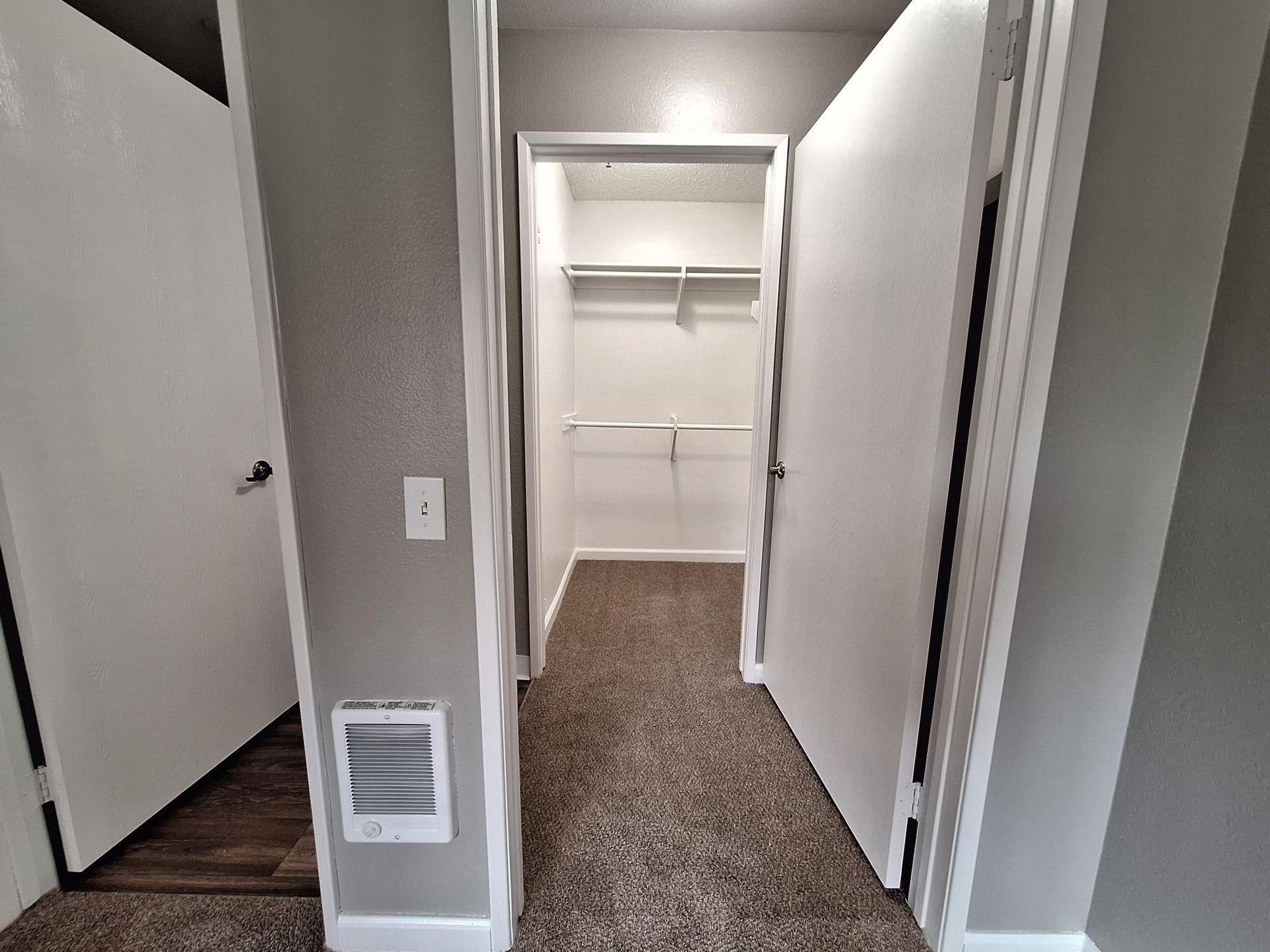 A hallway with a closet in the middle of it.
