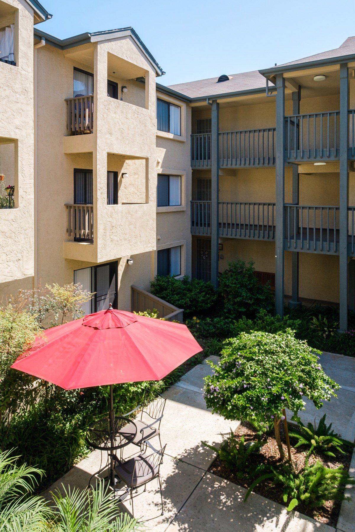 A red umbrella sits on a patio in front of a building