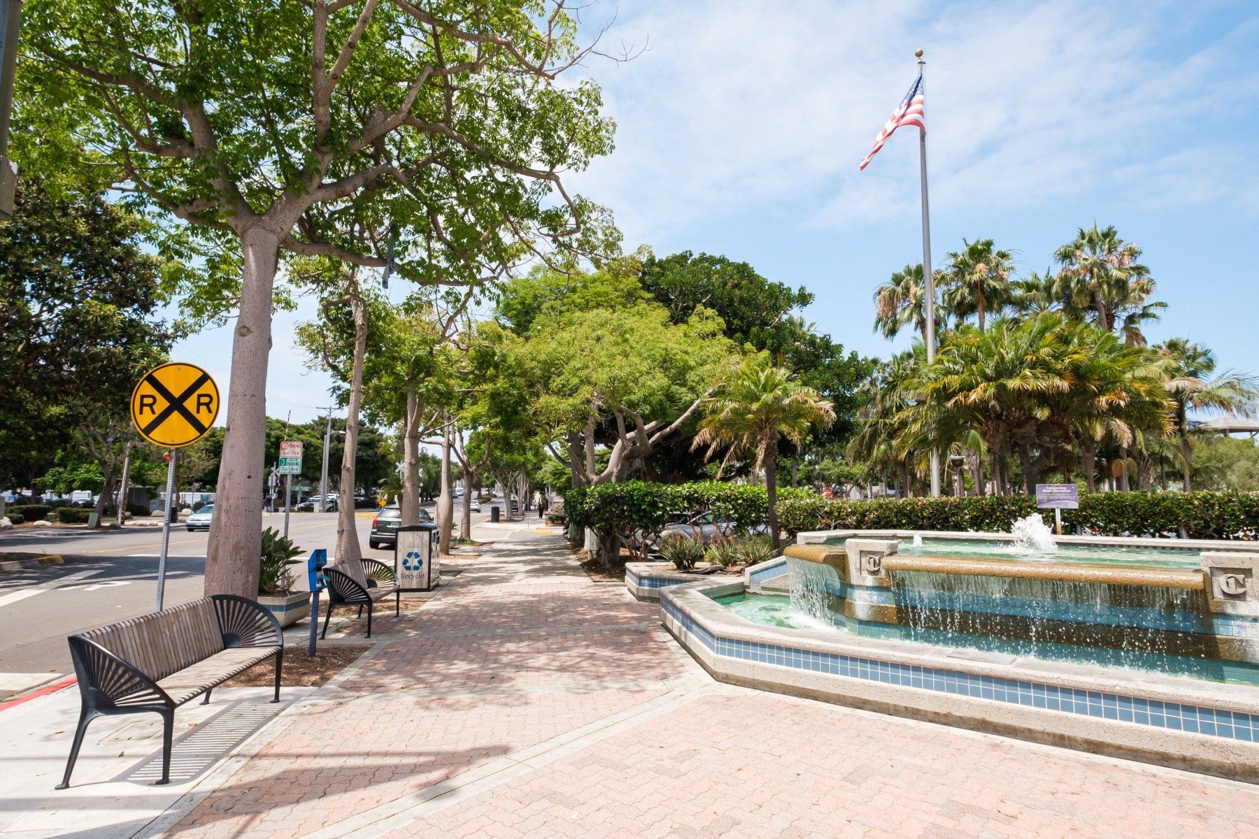 A park with a fountain and a railroad crossing sign