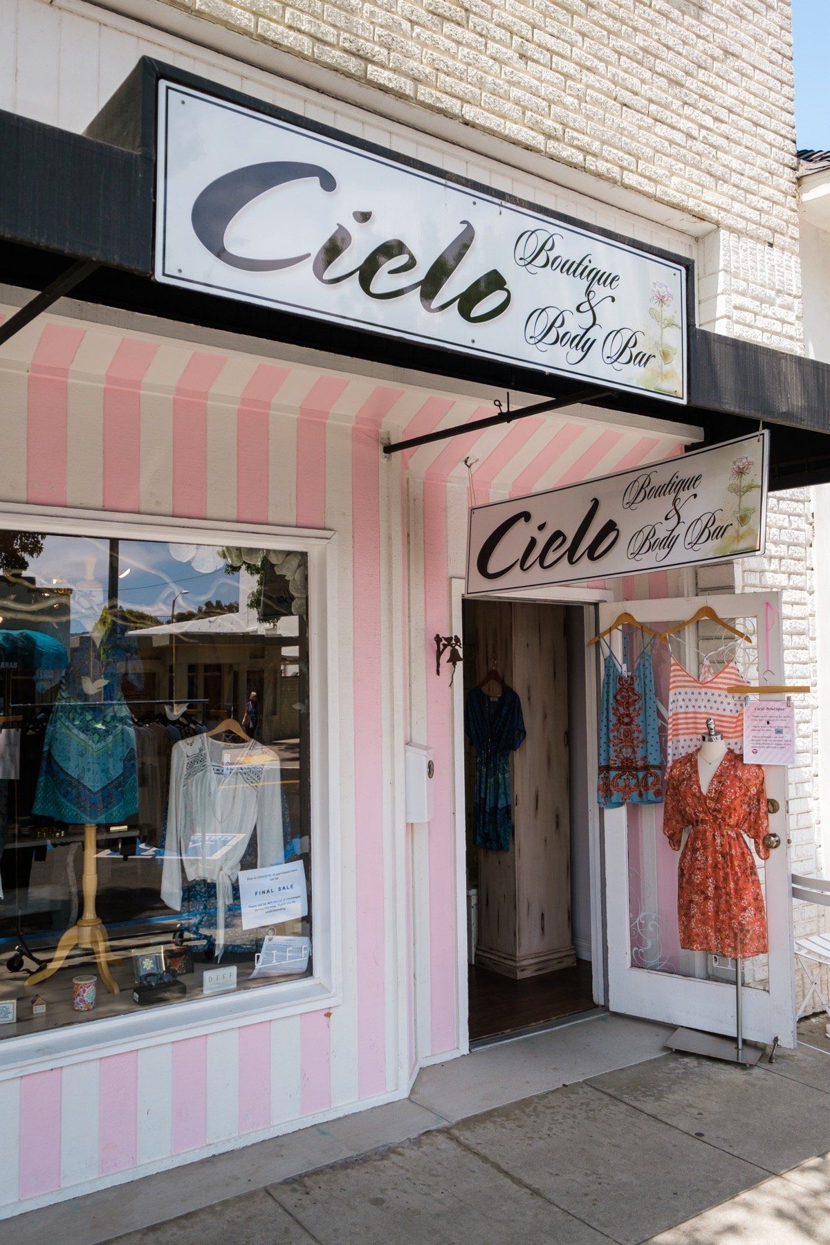 A pink and white striped store front with a sign above it.