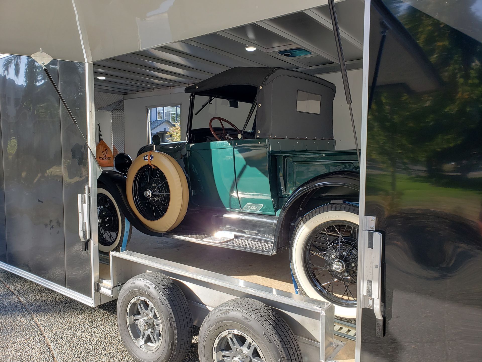 An old green truck is sitting on top of a trailer.