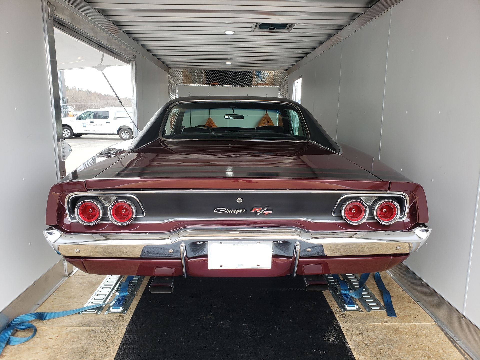 A red dodge charger is parked in a trailer.