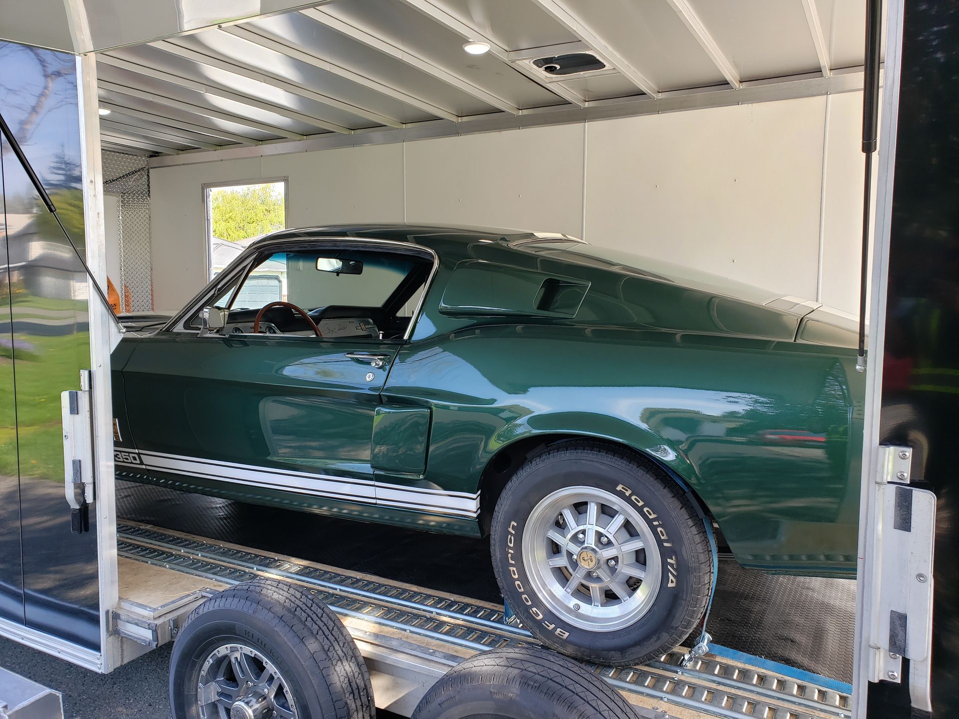 A green mustang is sitting on top of a trailer.