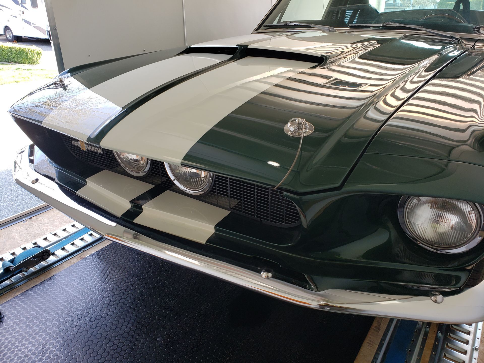 A green and white mustang is parked in a garage.