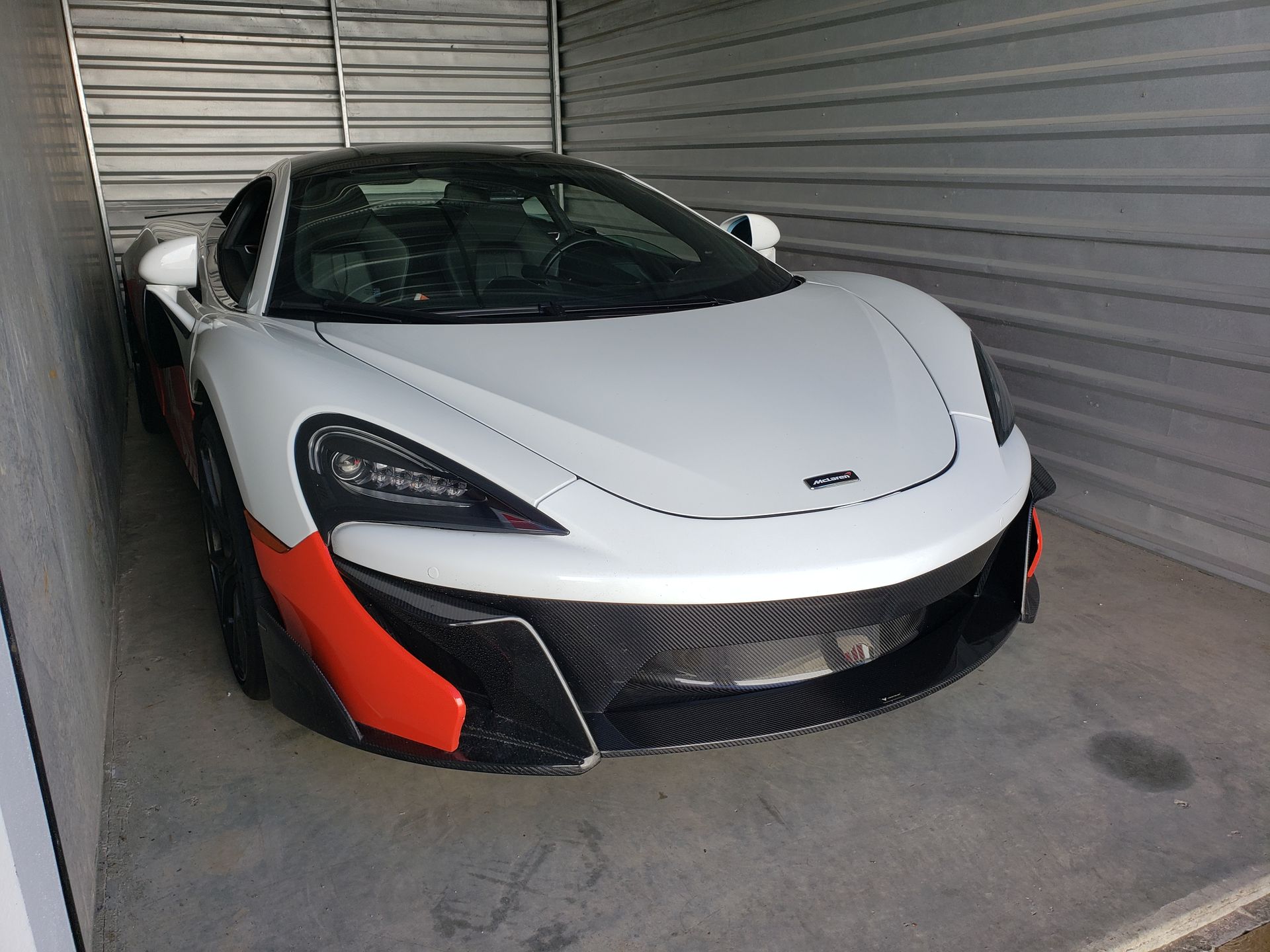 A white and red sports car is parked in a garage.