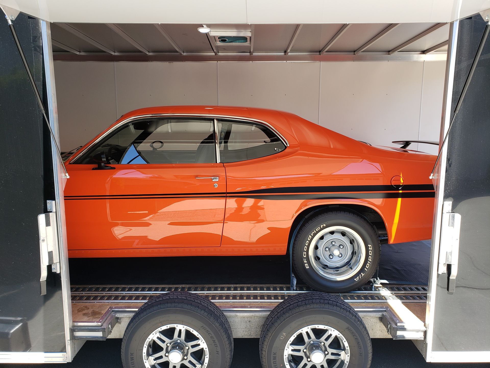 An orange car is parked in the back of a trailer