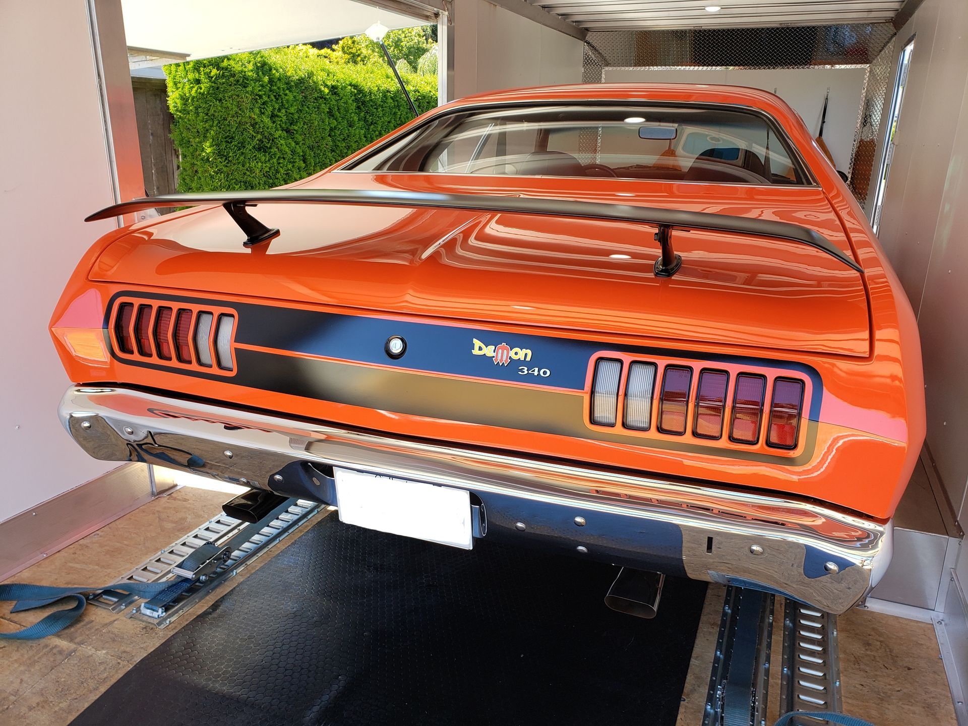 An orange dodge dart is parked in a garage