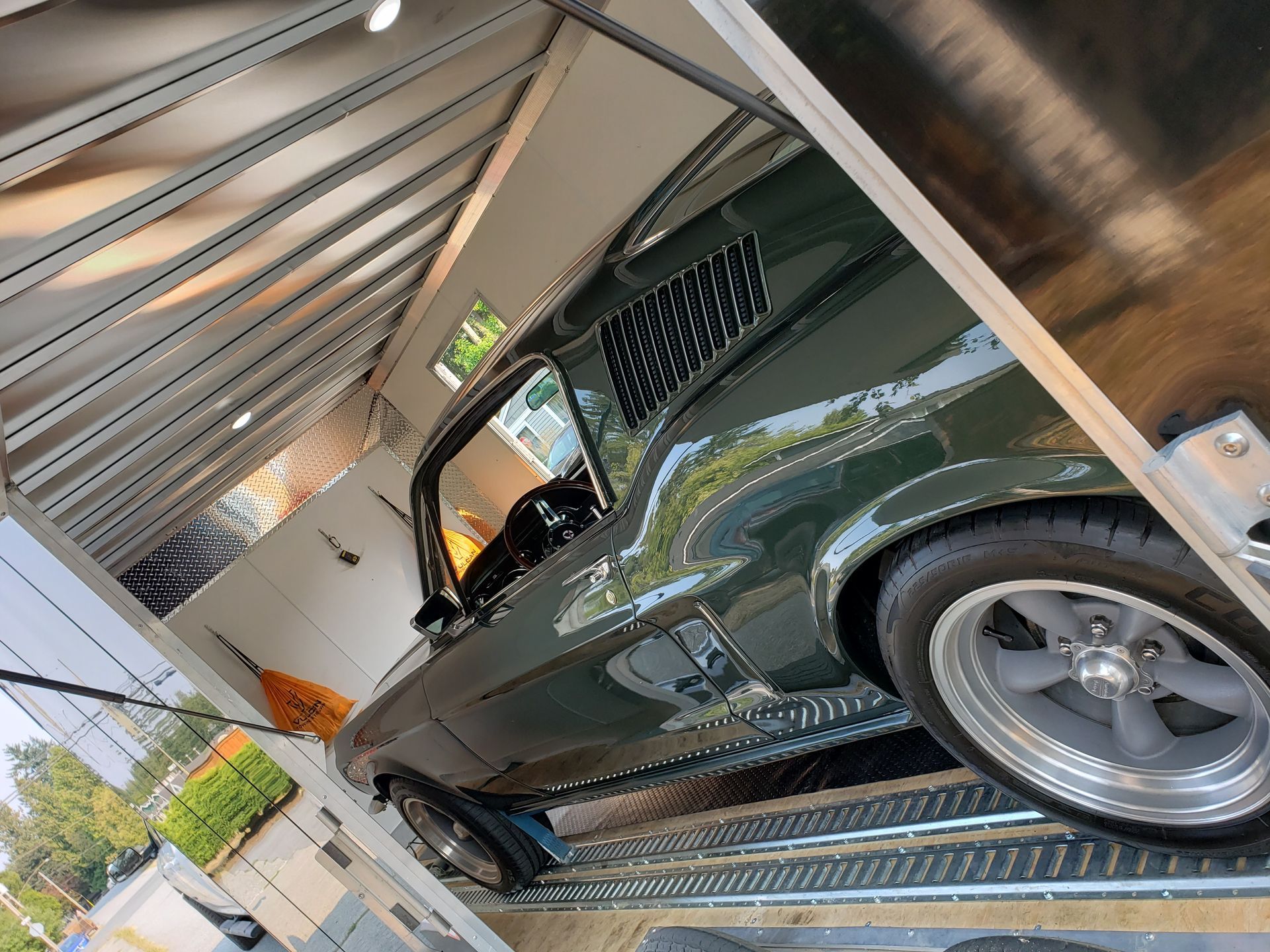 A green mustang is parked inside of a trailer