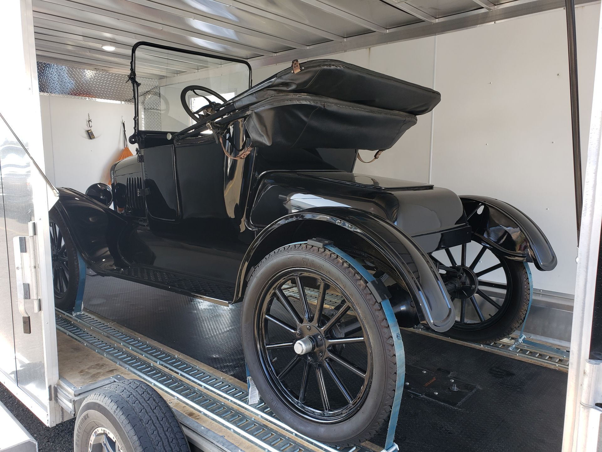An old black car is sitting on top of a trailer.