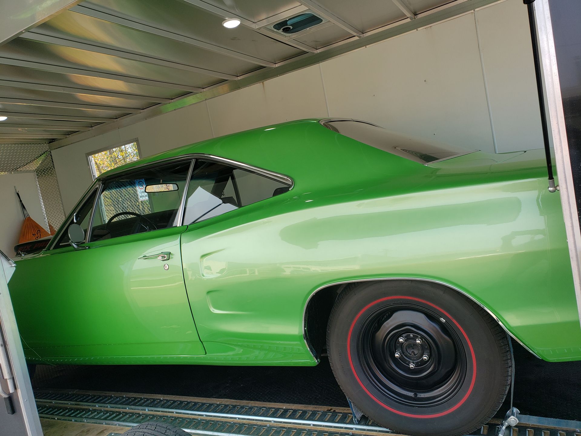 A green car is parked in a garage next to a trailer.