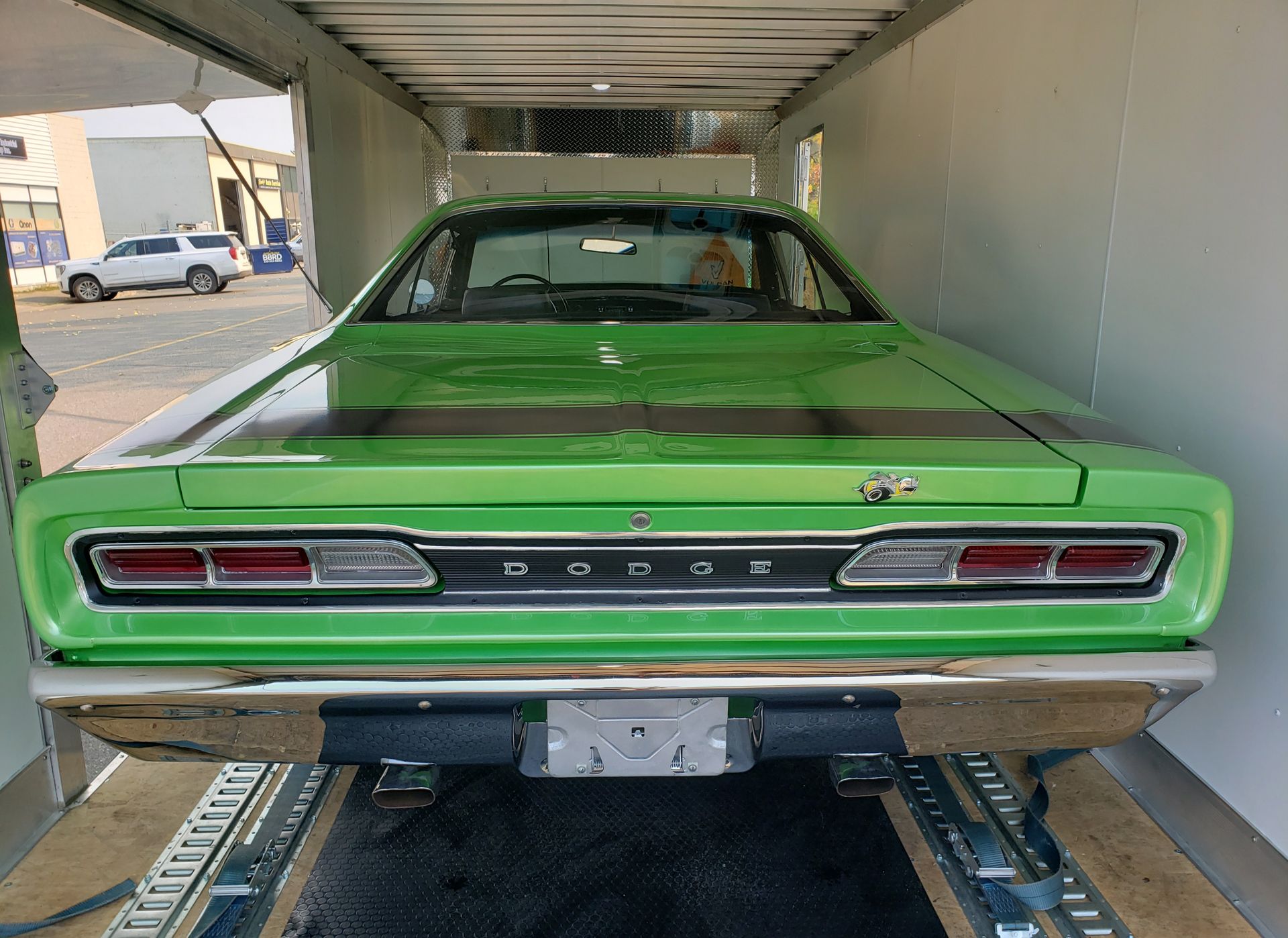 A green dodge charger is being transported in a trailer