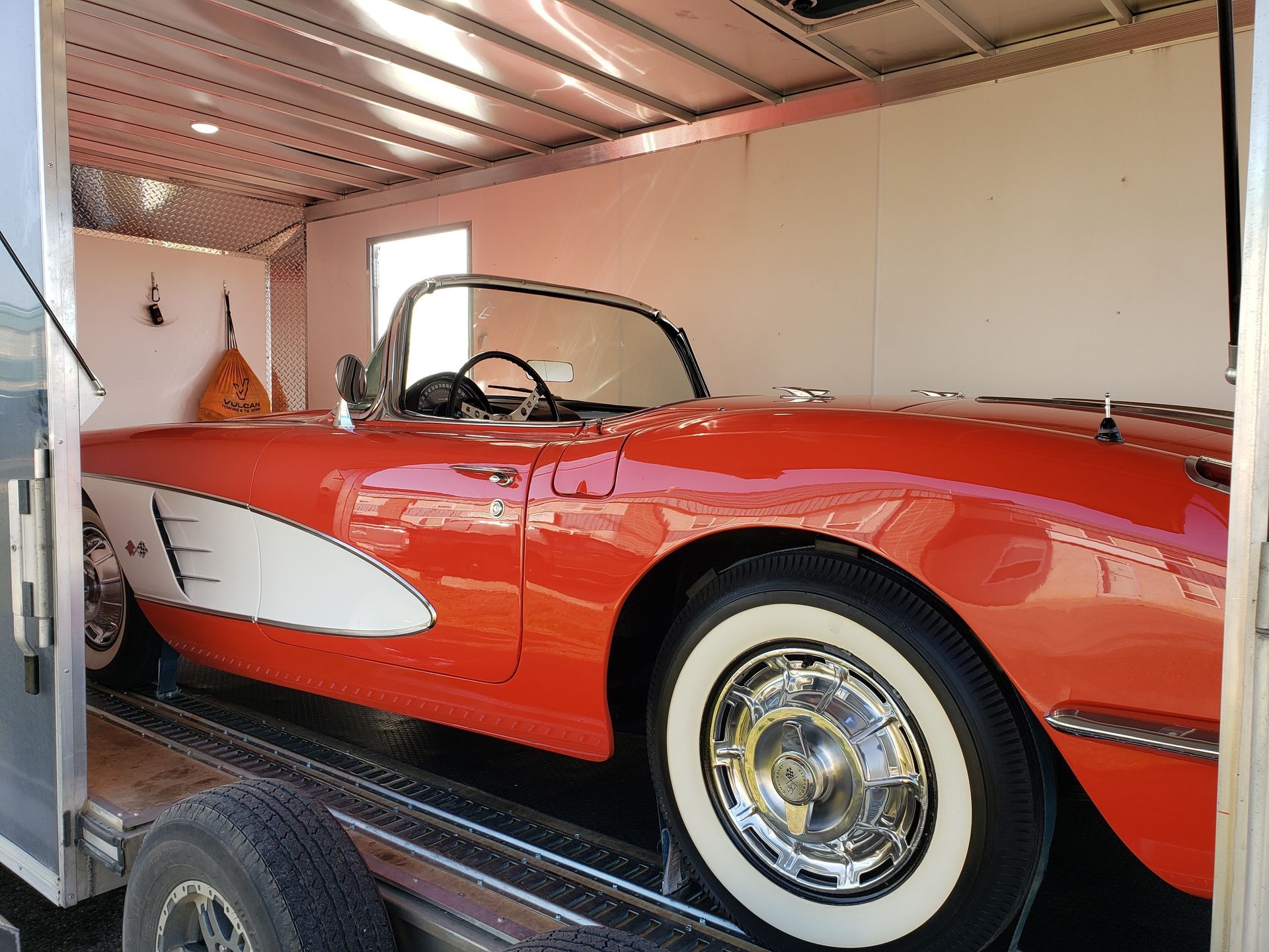 A red and white corvette is parked in a trailer.