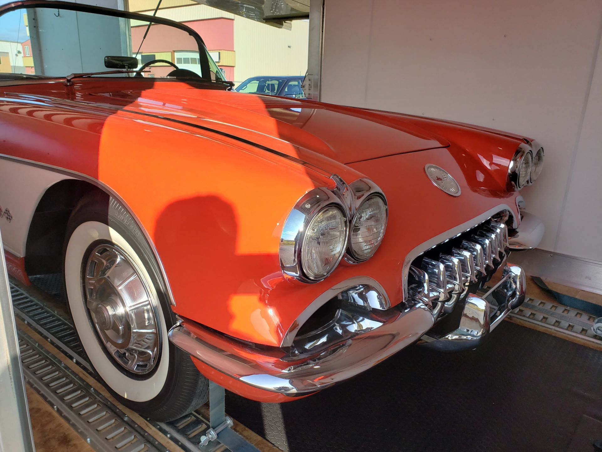 A red car with white tires is parked in a garage