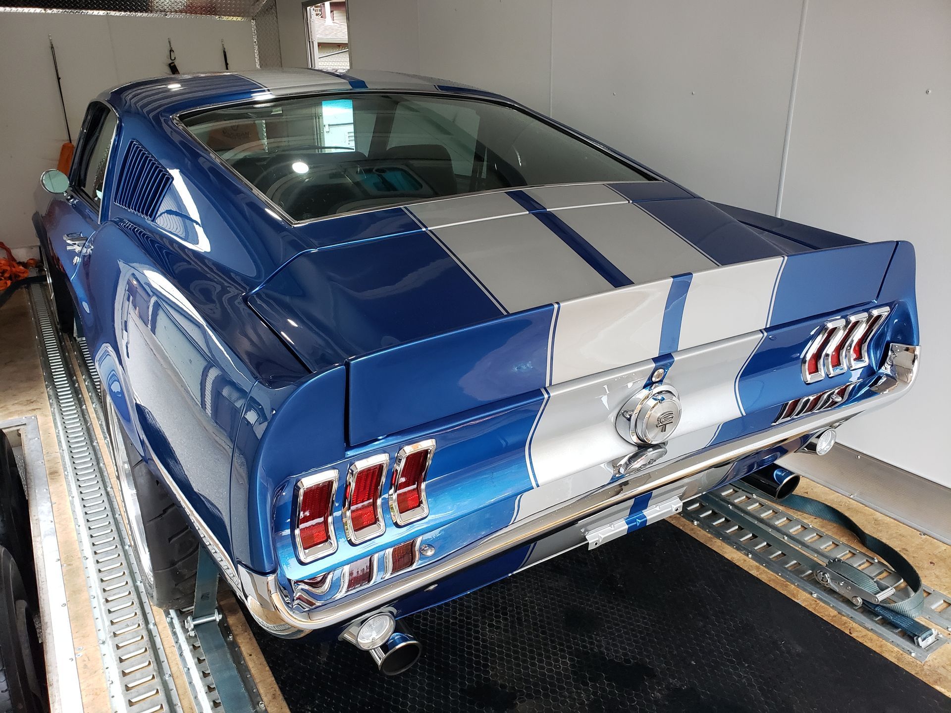 A blue and silver mustang is parked in a garage