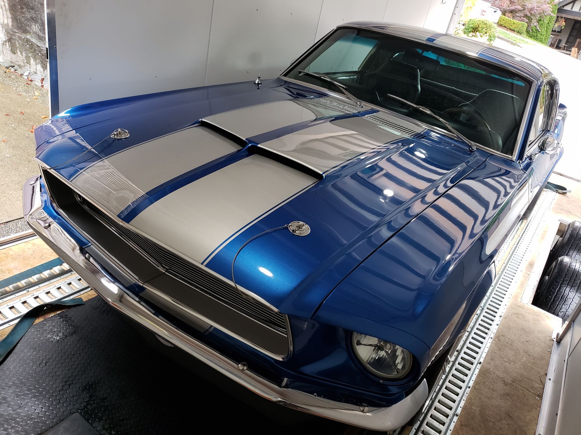 A blue and white mustang is parked in a garage.