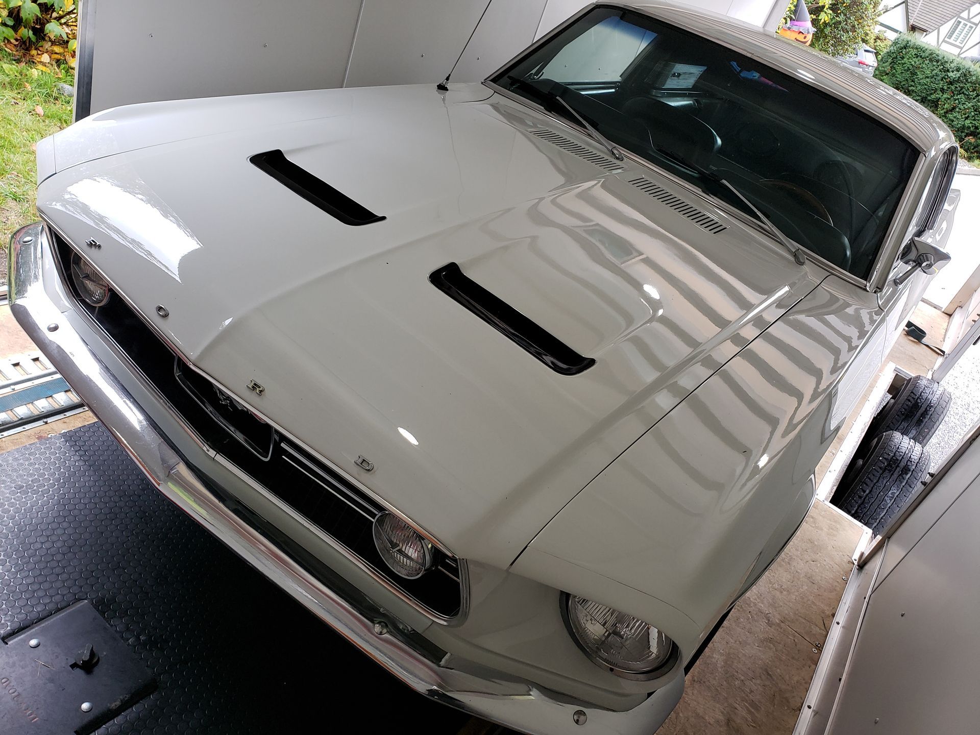 A white ford mustang is parked in a garage
