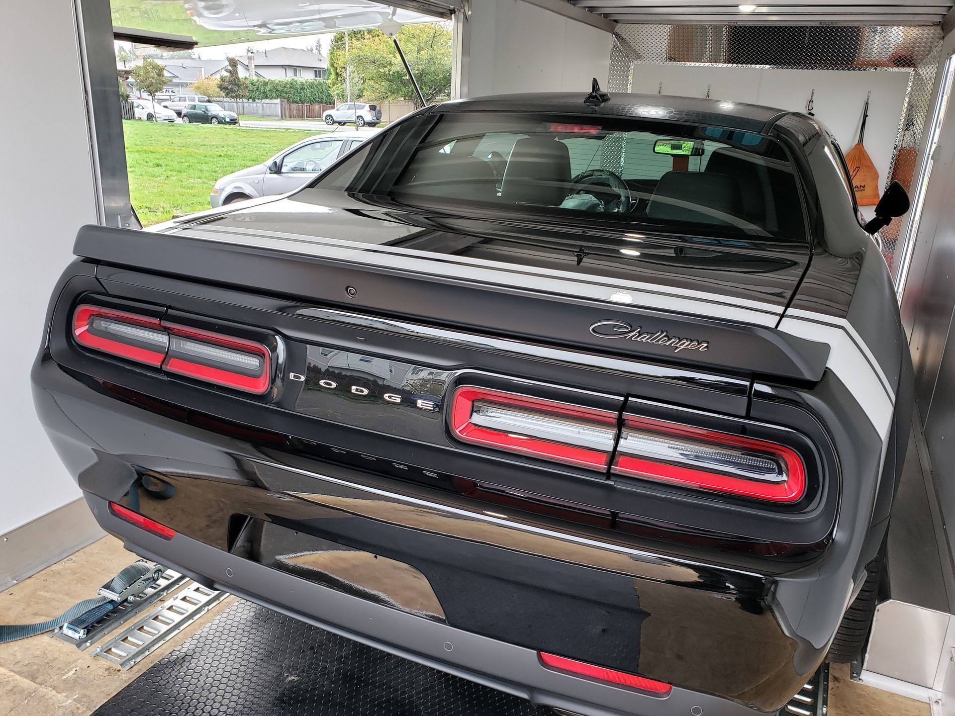 A black dodge challenger is parked in a garage.