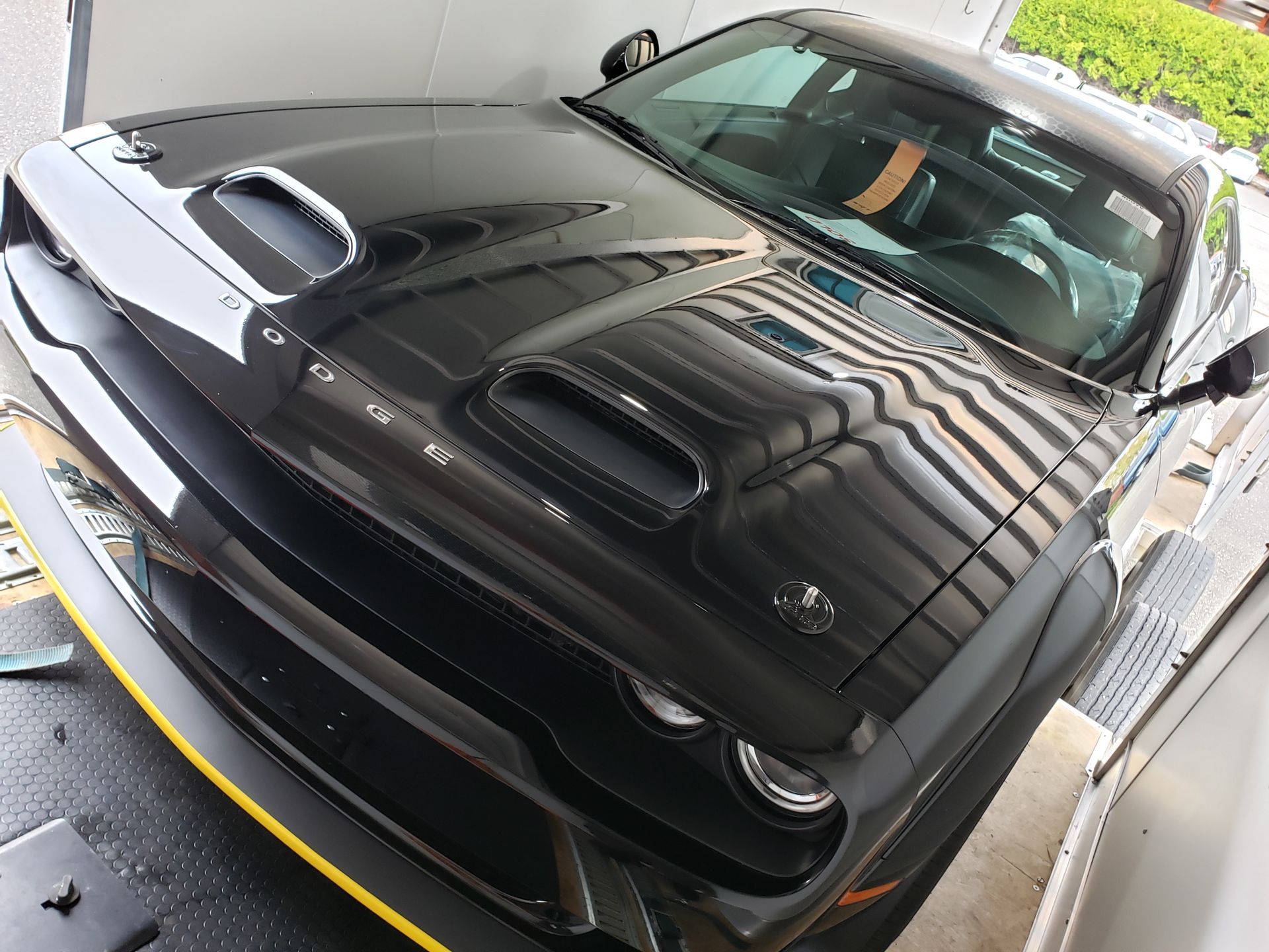A black dodge challenger is parked in a garage