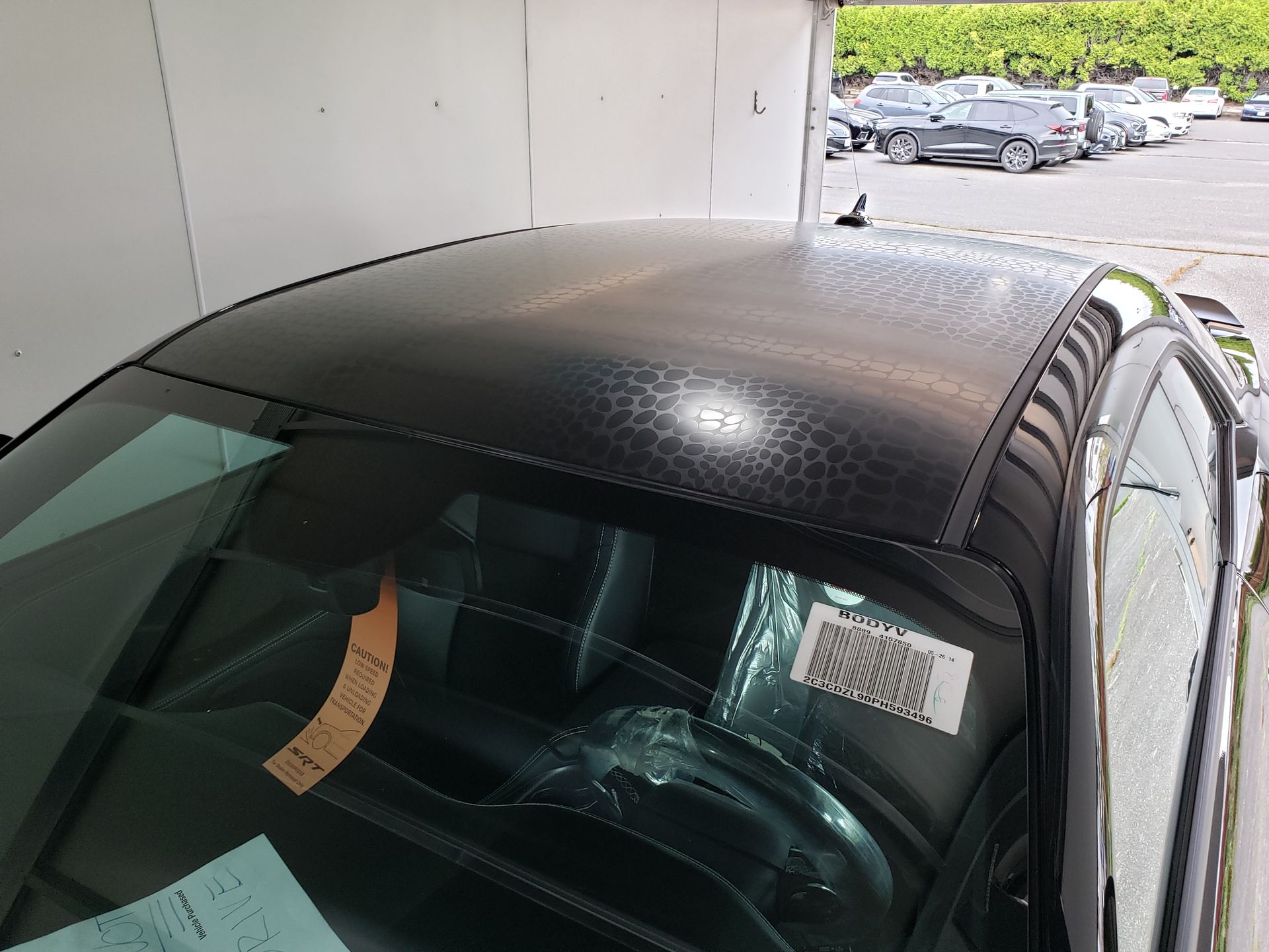 A car with a black roof is parked in a parking lot.