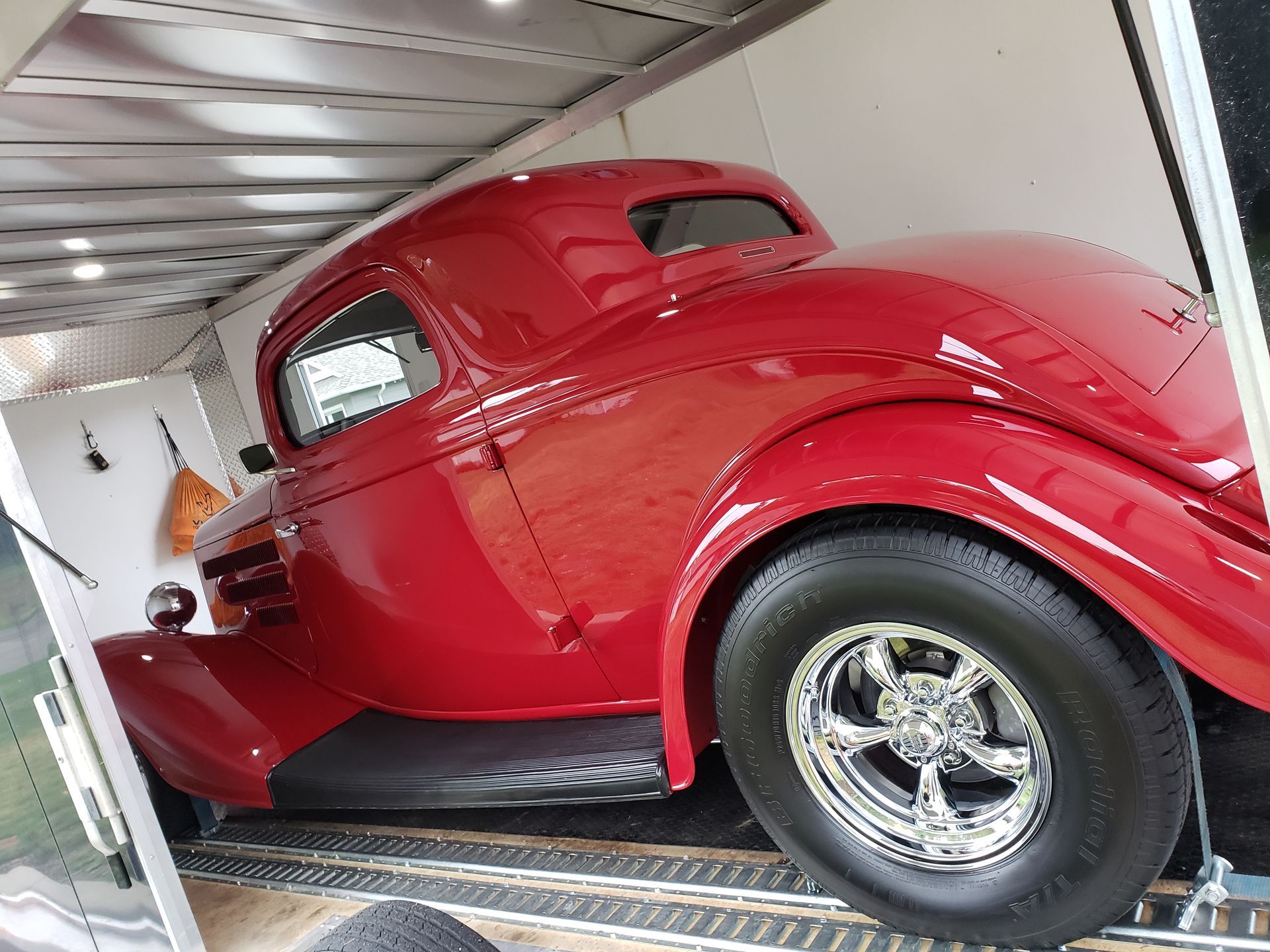 A red car is parked inside of a trailer.