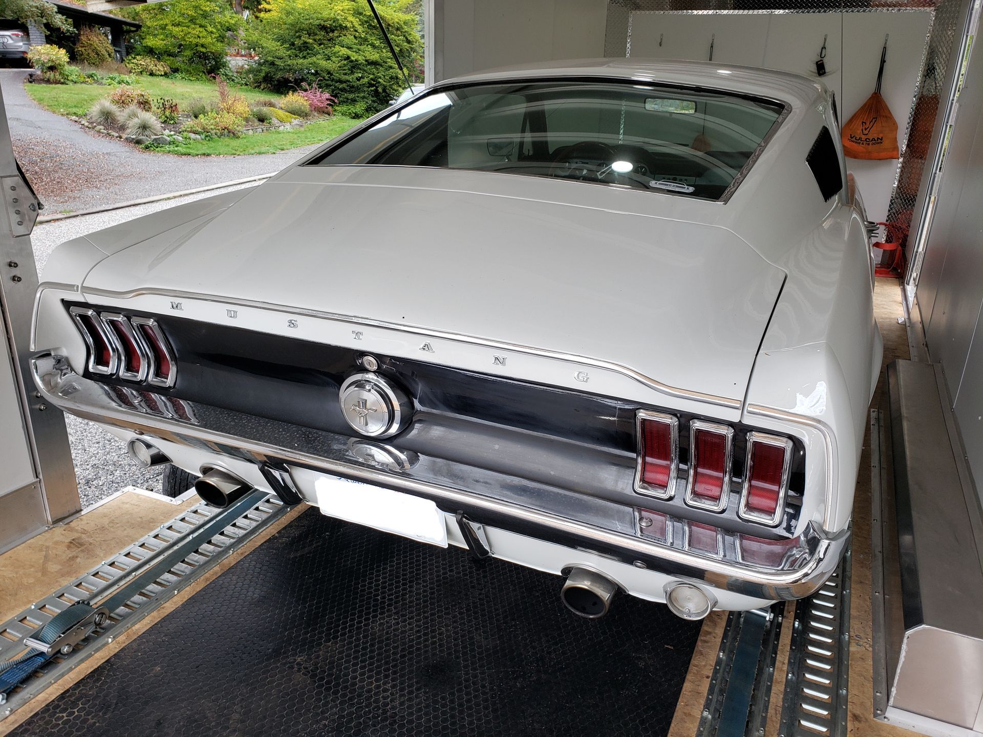 A white mustang is parked in a garage.