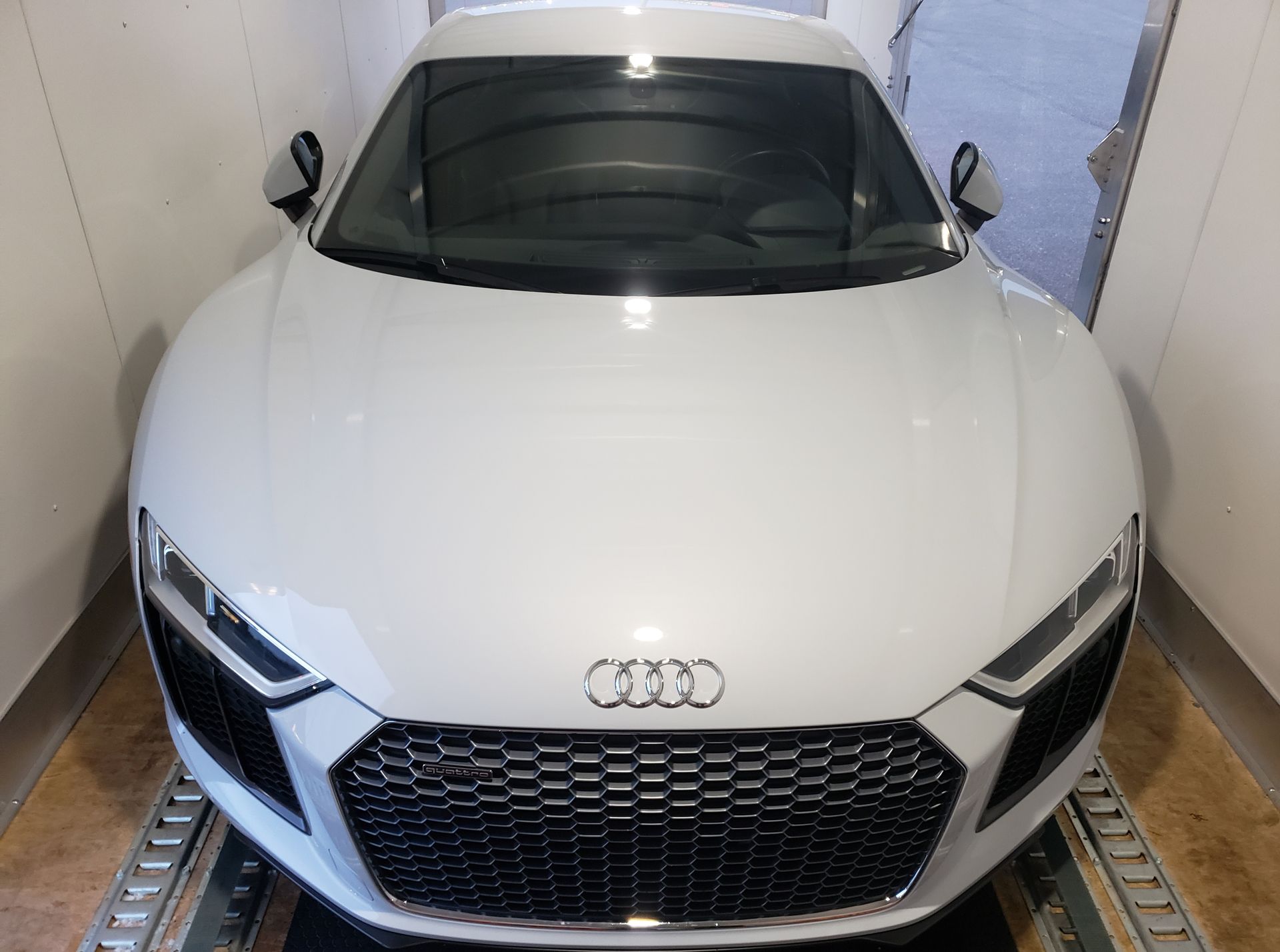 A white audi r8 is parked in a garage