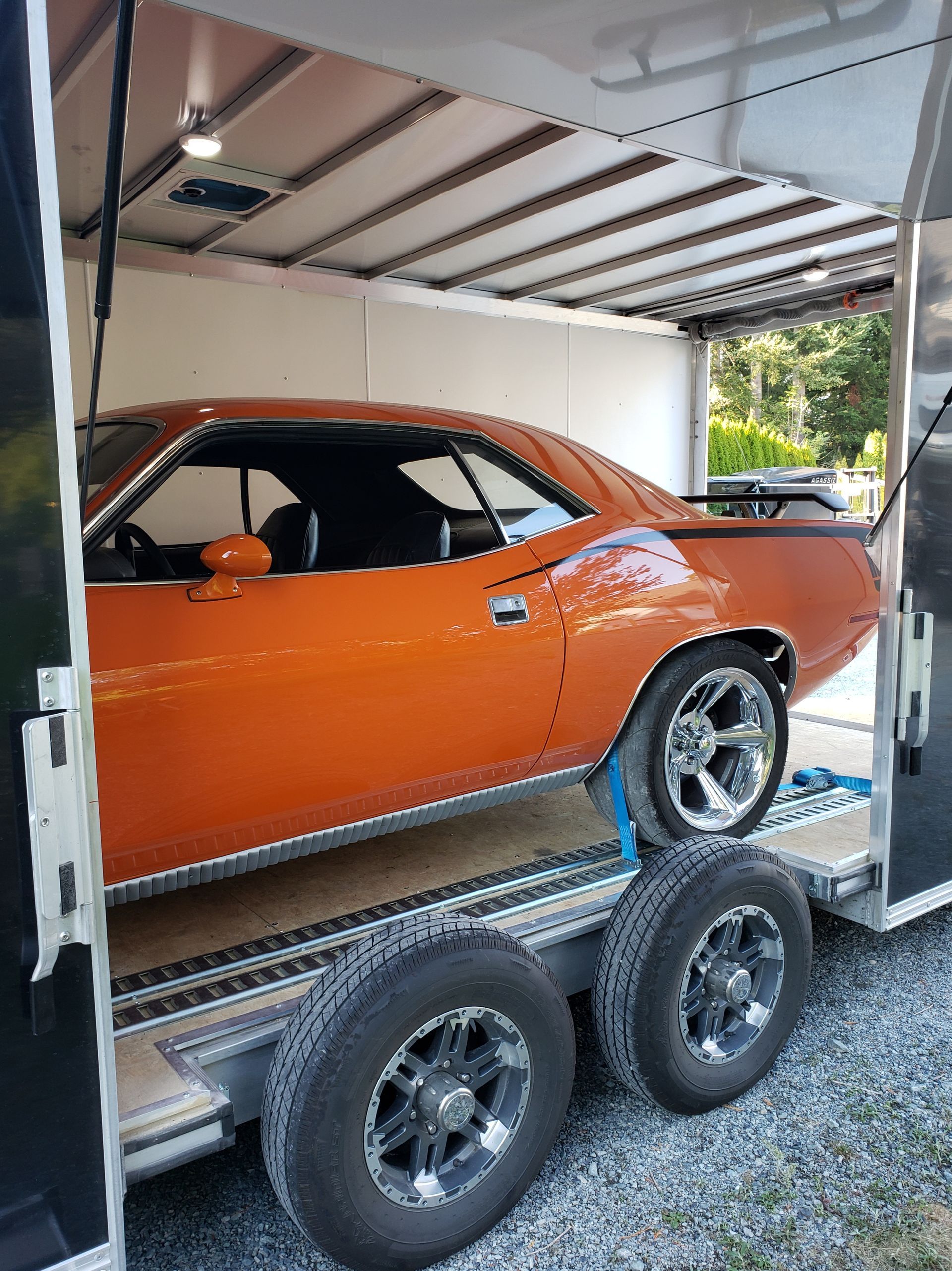 An orange car is sitting on top of a trailer.